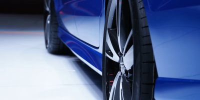 Close-up shot of a blue car highlighting the stylish alloy wheel. Perfect for automotive enthusiasts.
